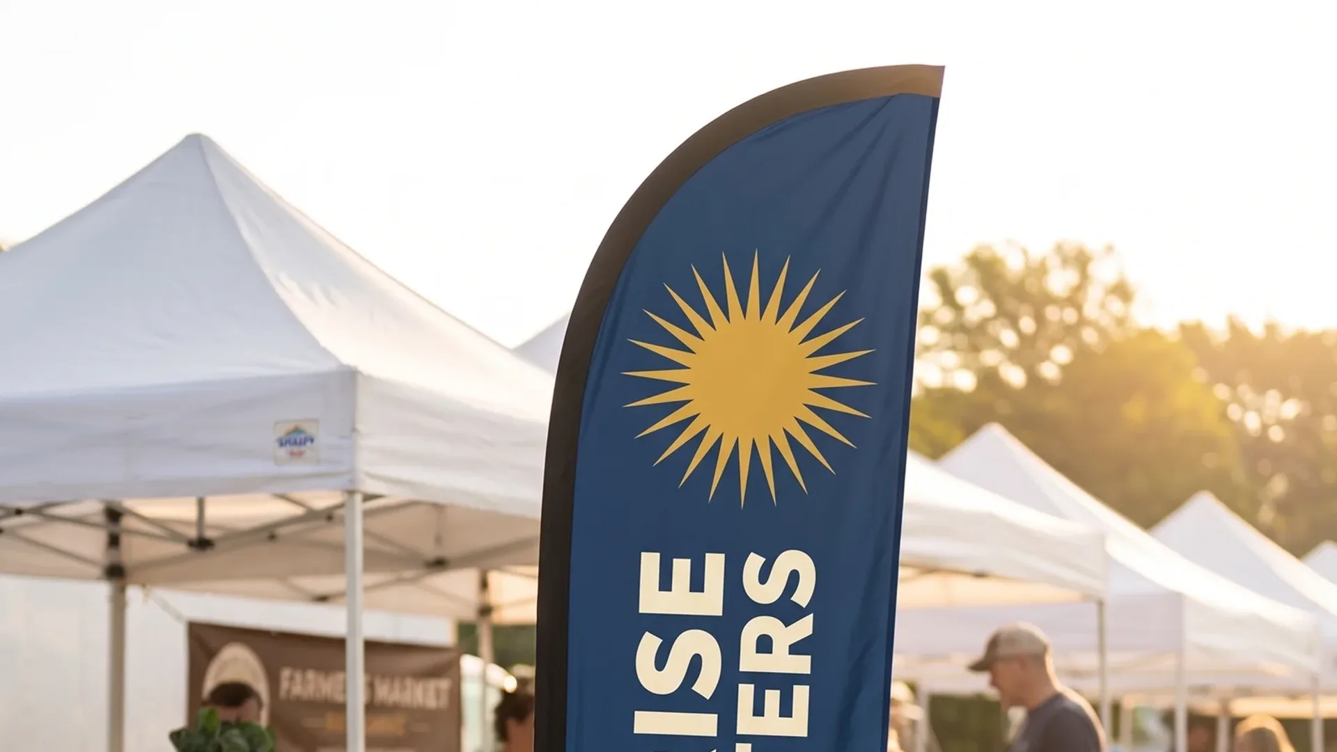 A blue custom feather flag standing on a lawn at an outdoor market