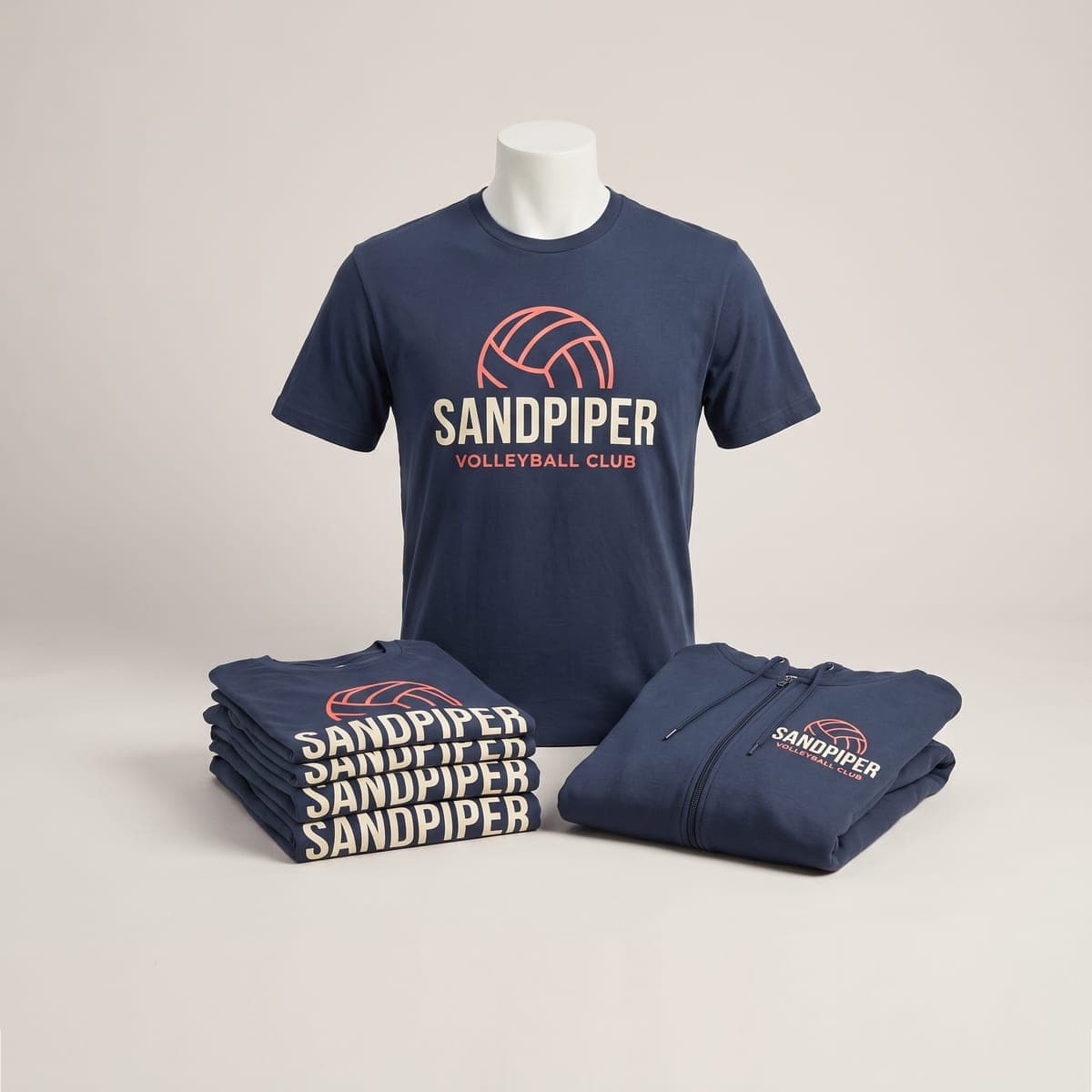 Slate navy Sandpiper Volleyball Club t-shirt, folded shirt stack and zip hoodie in a studio