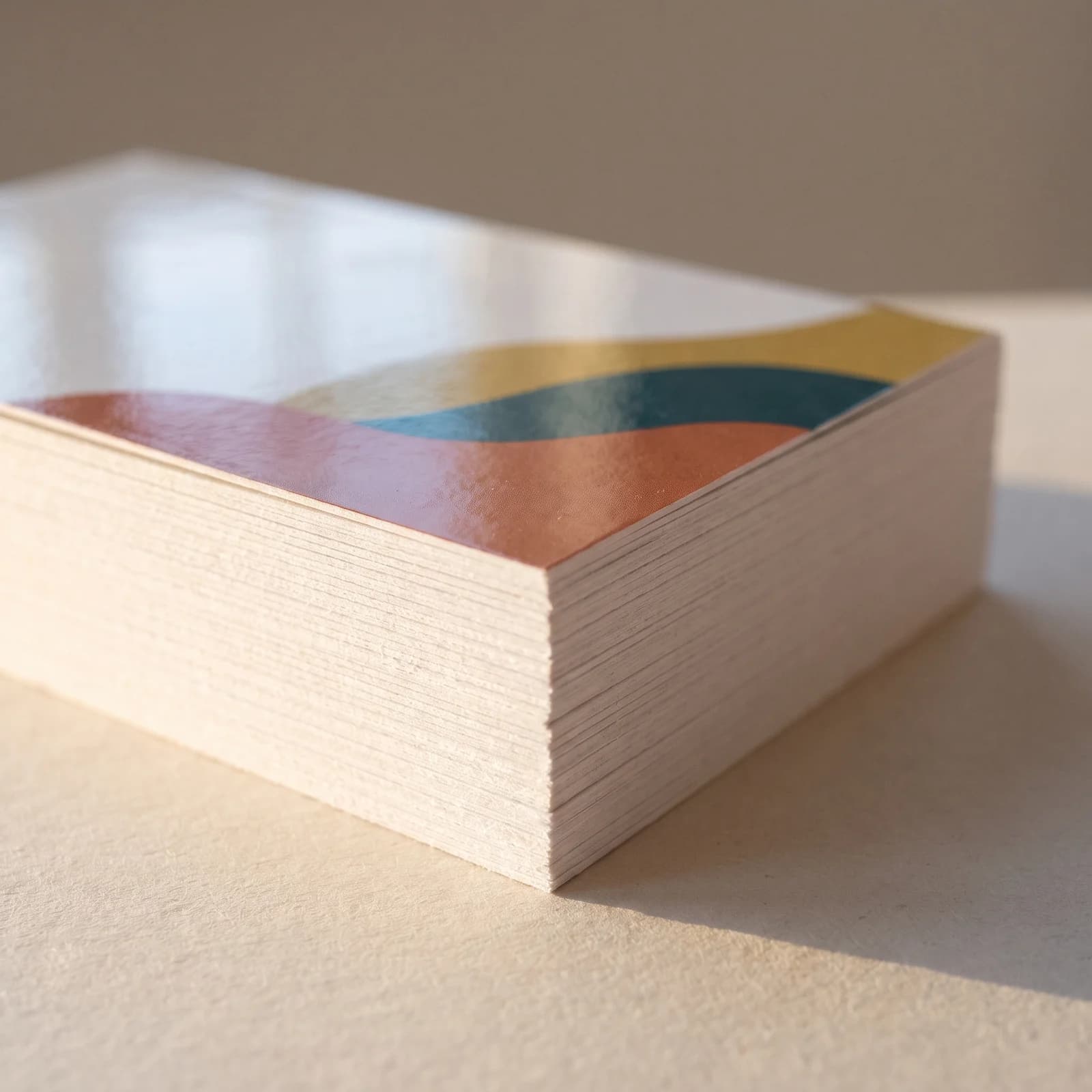 Macro view of the edge of a stack of 16pt gloss business cards with the printed face catching the light on top
