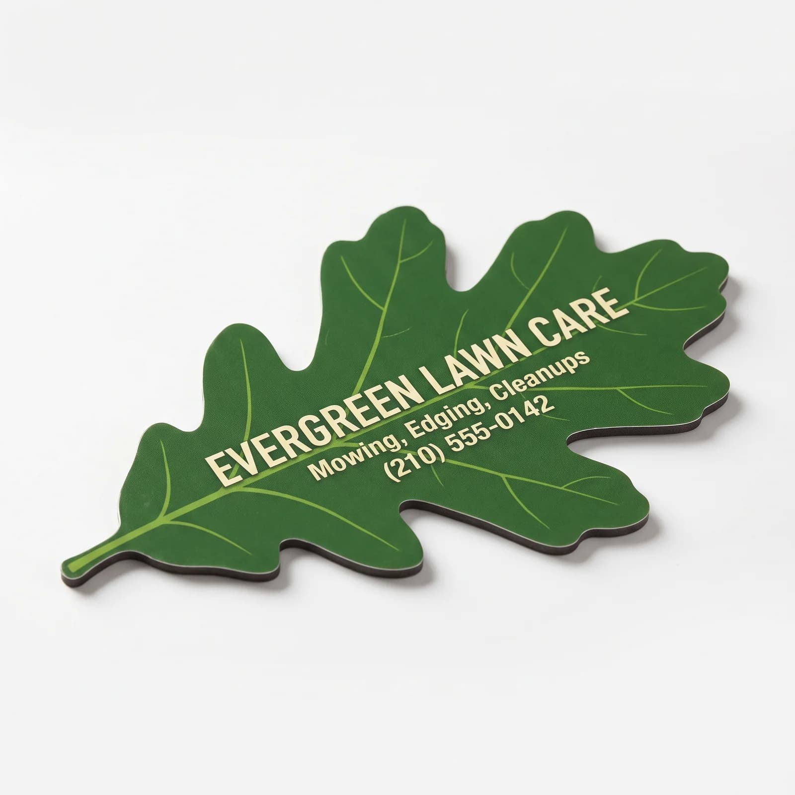 An oak-leaf contour-cut magnet for Evergreen Lawn Care on a white studio ground, cut to the leaf outline