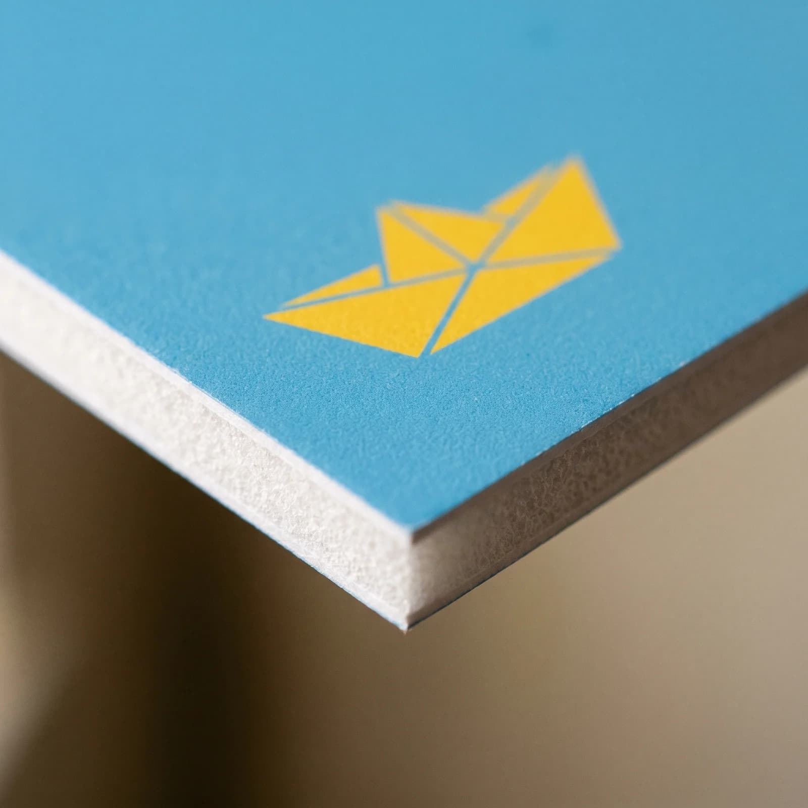 Close view of the white foam core edge under a printed blue foam board face