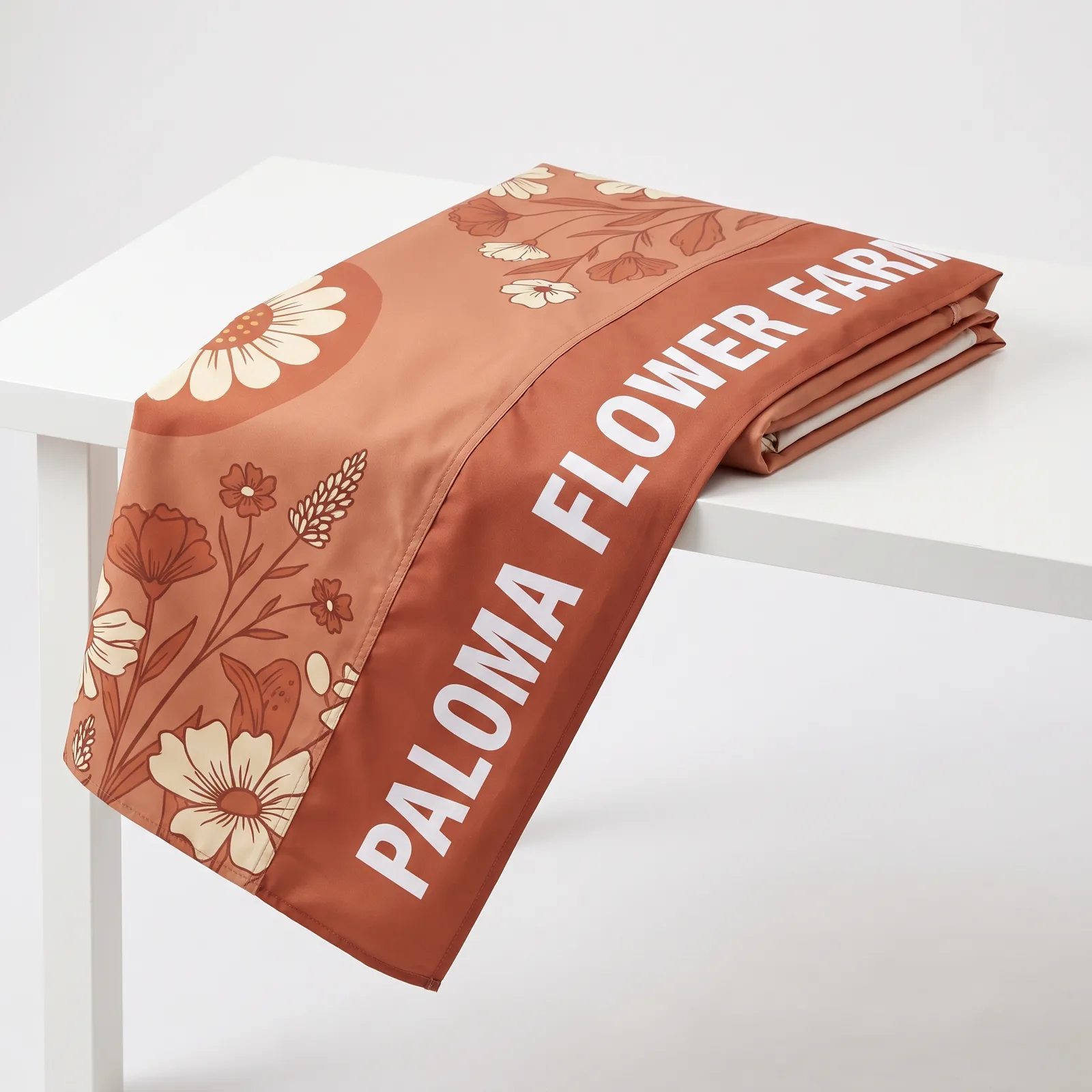 The same terracotta canopy top folded on a white table, a close view of a Paloma Flower Farm valance and a sewn seam