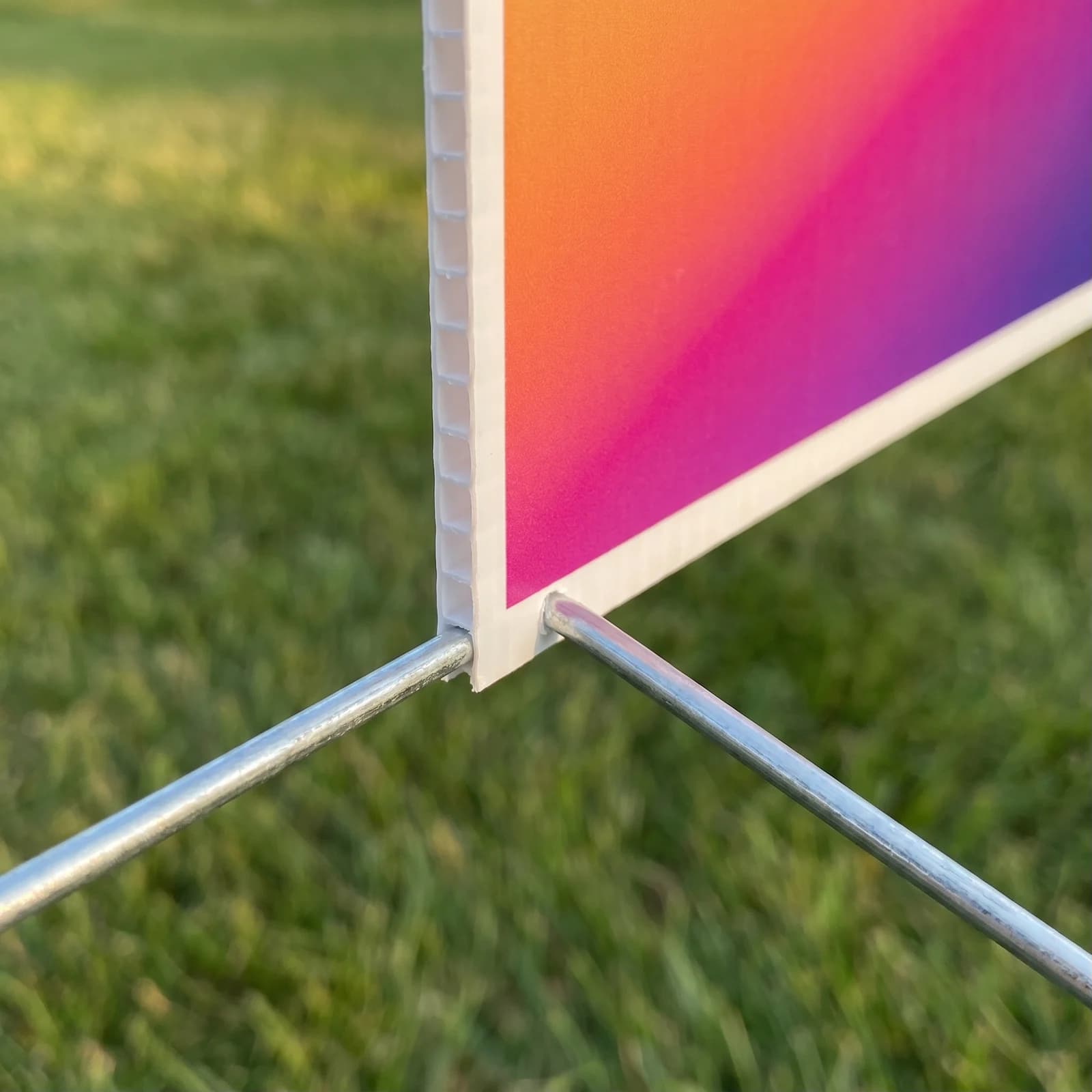 Close view of a full-color 12 x 18 inch coroplast sign edge with a wire H-stake seated in the flutes