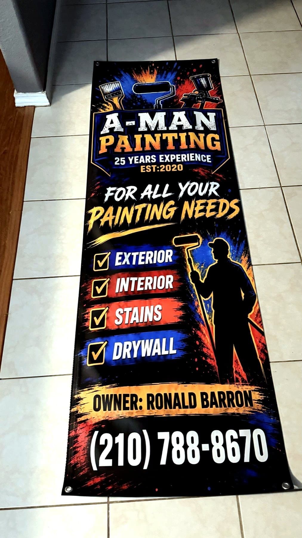 Delivery photo of the A-Man Painting banner laid flat indoors before pickup