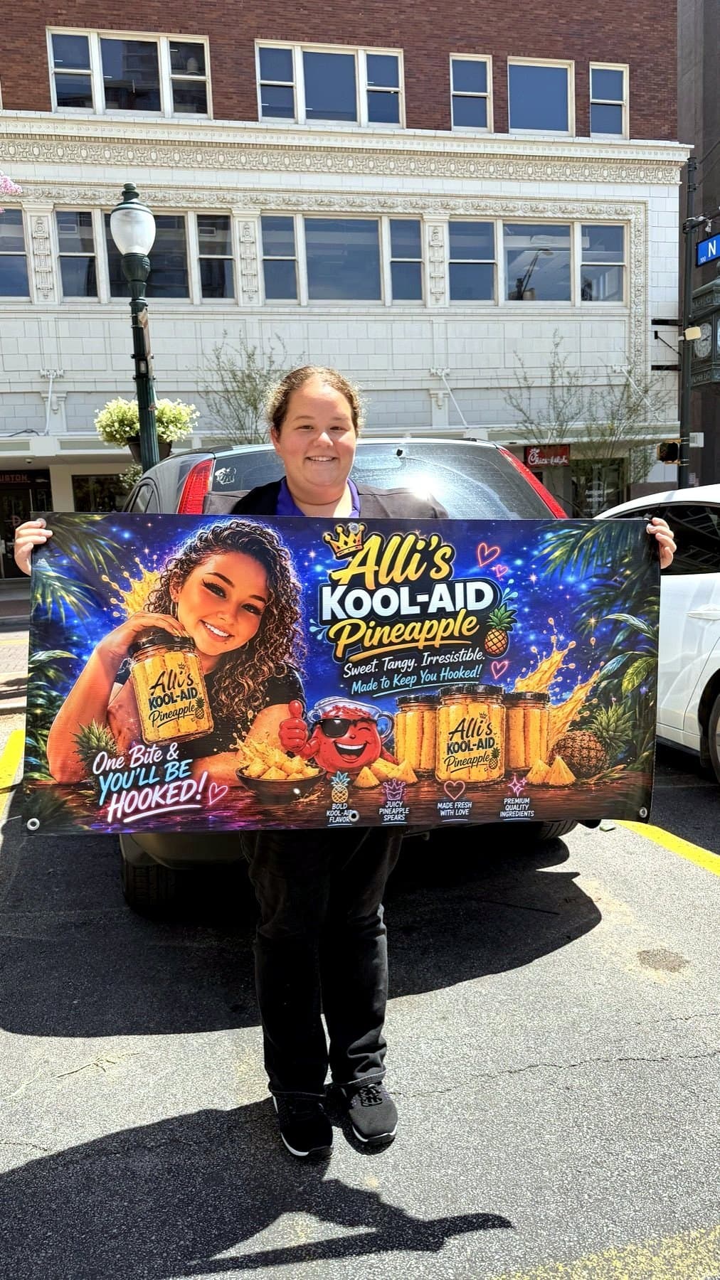 Pickup photo of the Alli's Kool-Aid banner held open by the owner in front of her vehicle