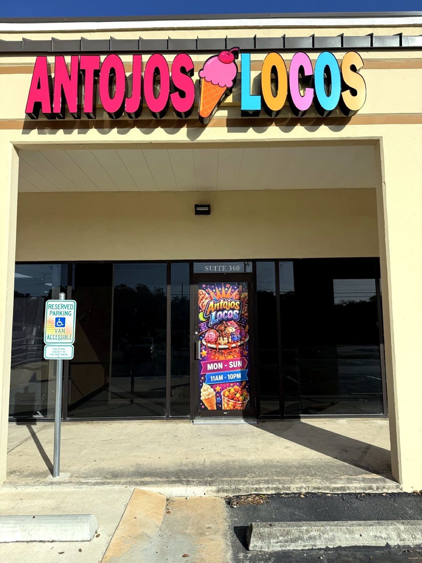 Install-day photo of the Antojos Locos letters and door graphic on the storefront, taken on site