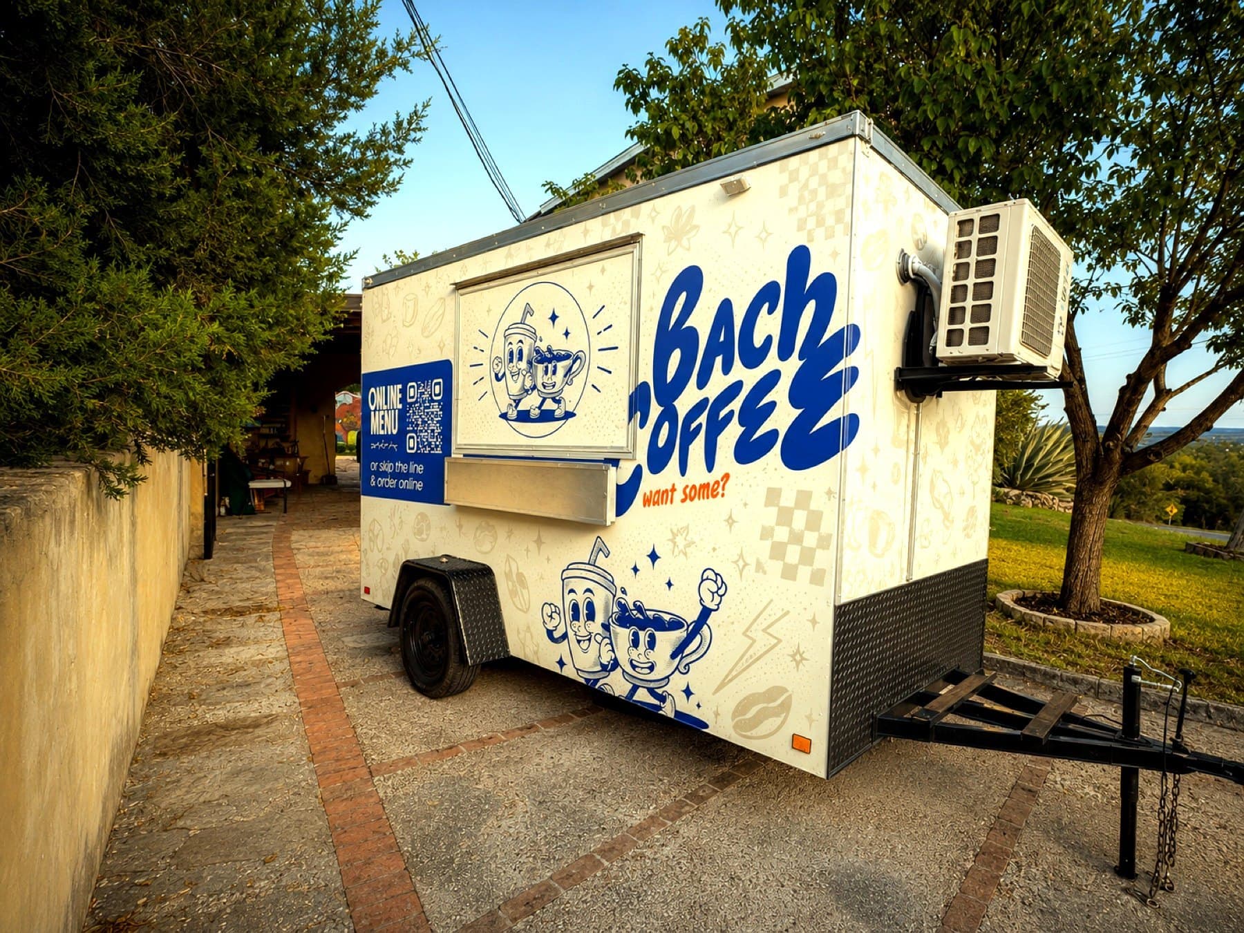 On-site photo of the wrapped Bach Coffee trailer from the rear corner