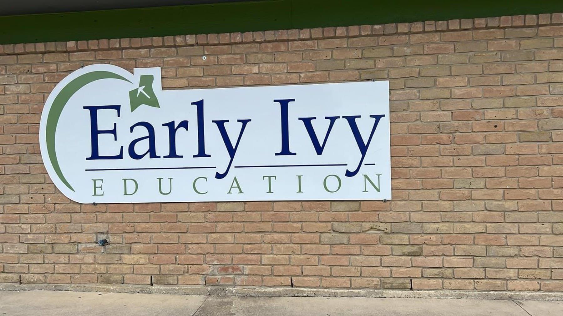 The Early Ivy Education wall panel on the same brick before the rebrand