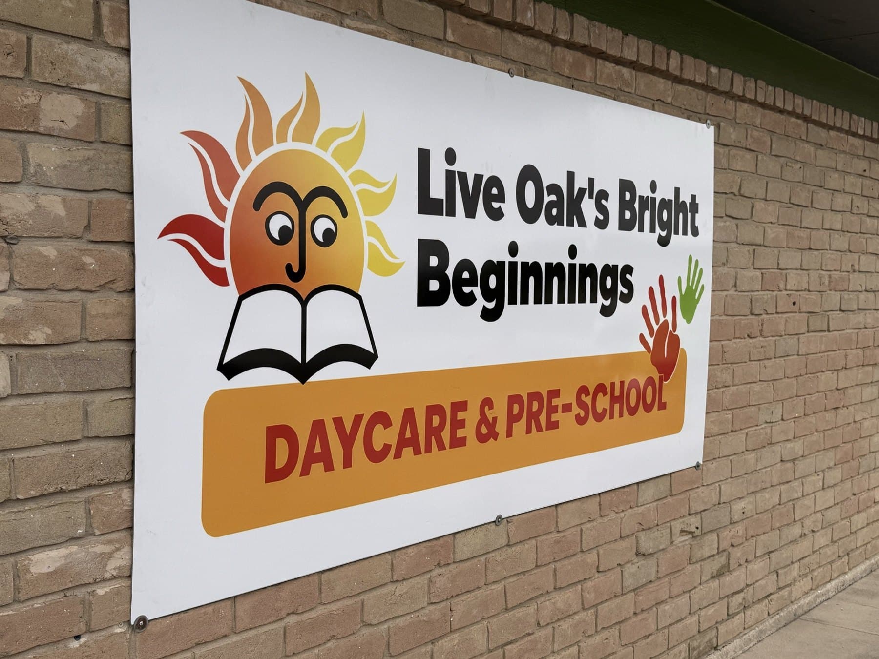 Install-day photo of the Bright Beginnings wall sign on the brick beside the entrance, taken on site