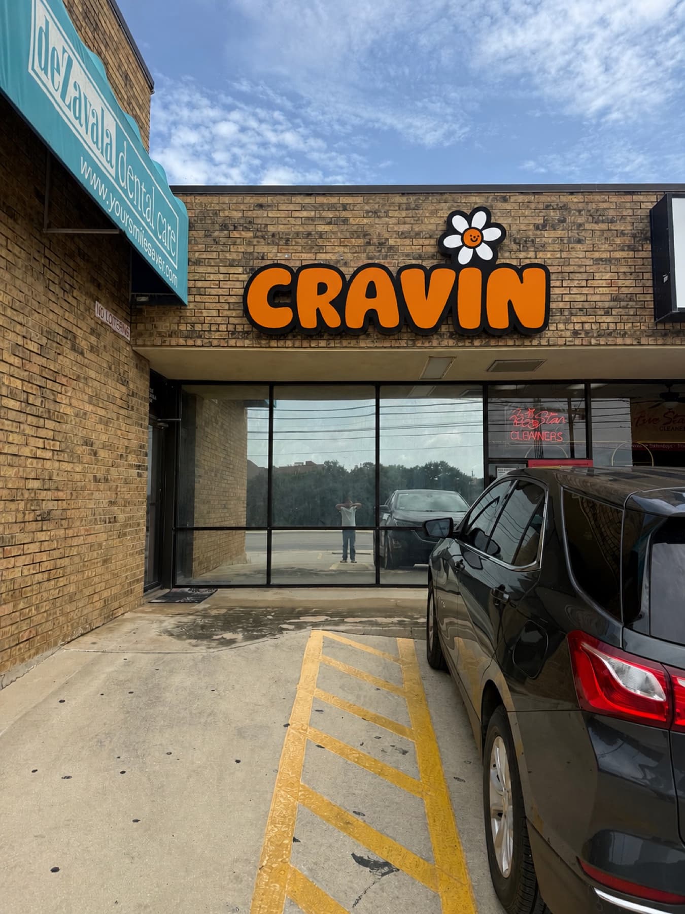 The Cravin sign in daylight from the parking lot, unlit, showing the dark returns around each letter