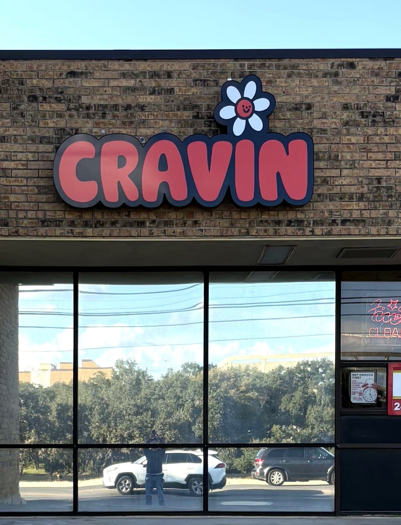 Install-day photo of the Cravin sign on the brick fascia, taken on site from the parking lot