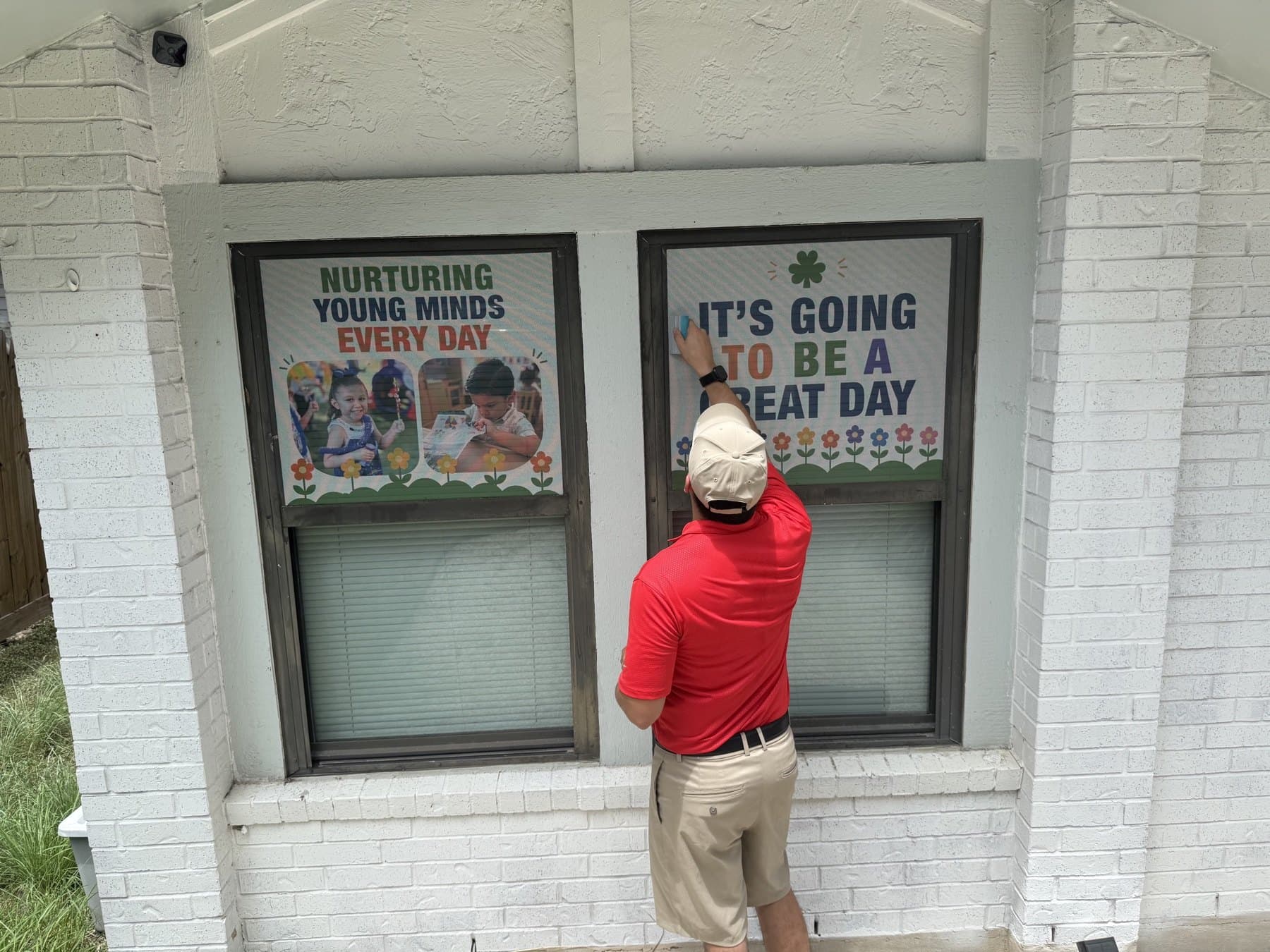 Installer applying a Growing Minds window panel on another elevation of the building