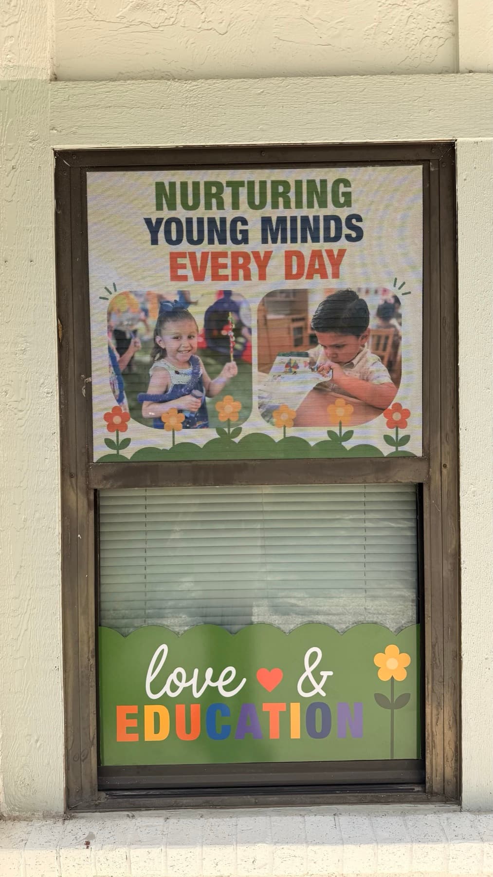 Close view of the Nurturing Young Minds Every Day window panel with two children's photos and the Love and Education band below