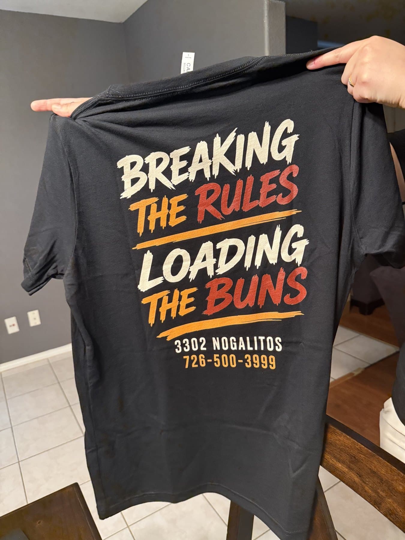 The back of the Loaded Buns crew shirt with the tagline, address and phone number