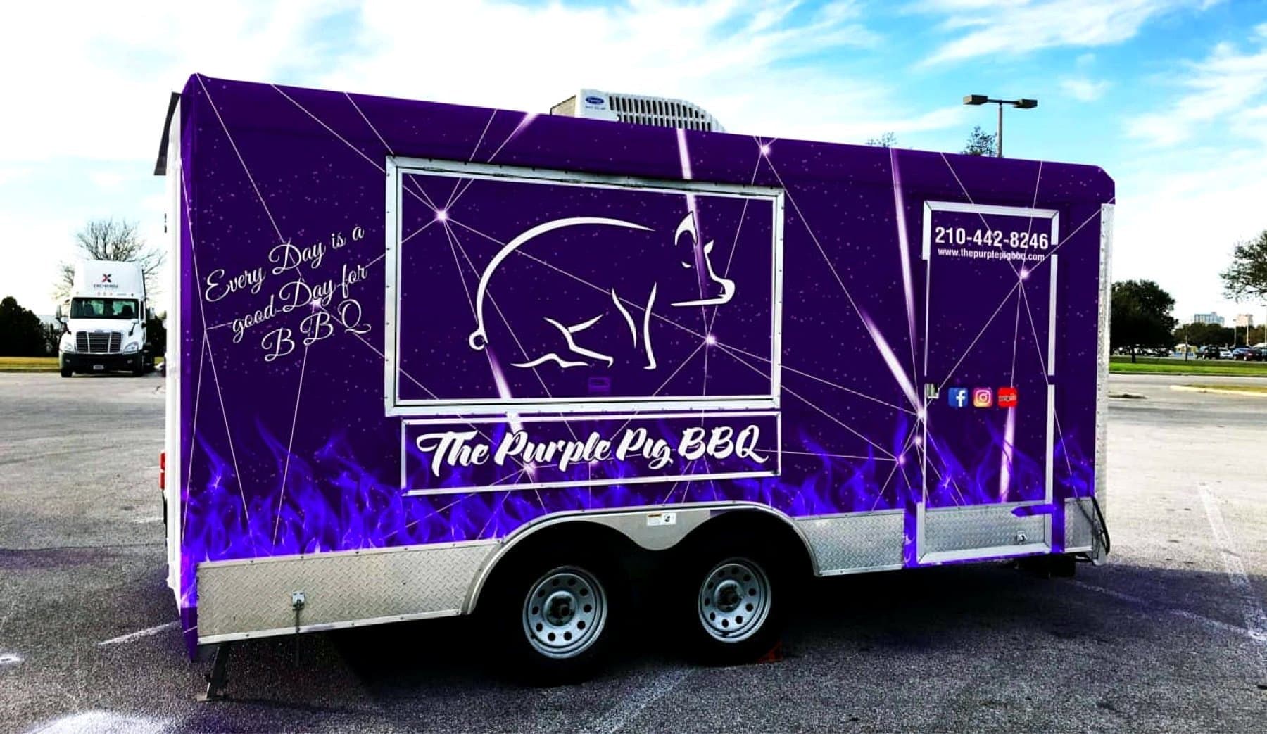 On-site photo of the wrapped Purple Pig BBQ trailer in the lot