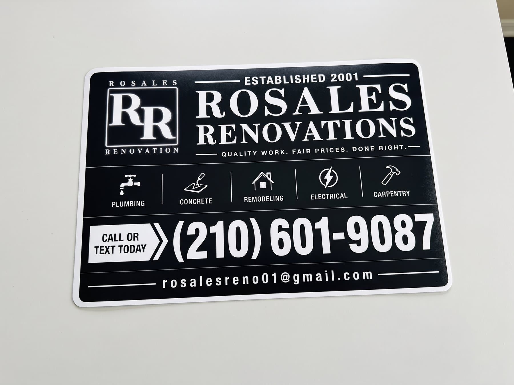 Rosales Renovations vehicle magnet photographed flat, with the RR mark, five service icons and labels across the middle, and the phone number in the largest type on the panel