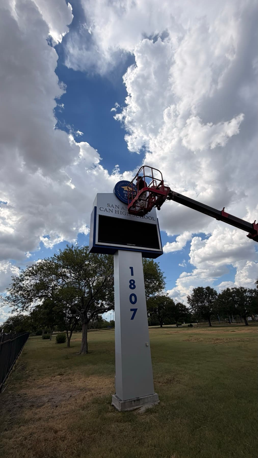 Full view of the San Antonio Can High School pylon sign with the crane bucket at the top and the 1807 address on the pole