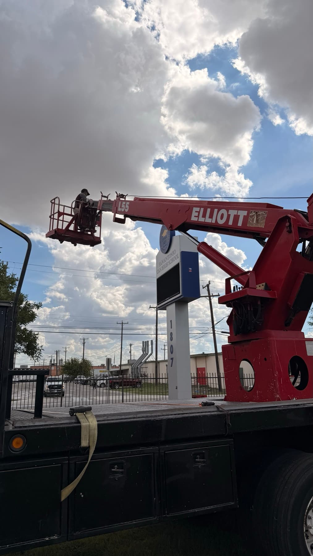 Crane truck with its boom extended to the top of the pylon sign during installation
