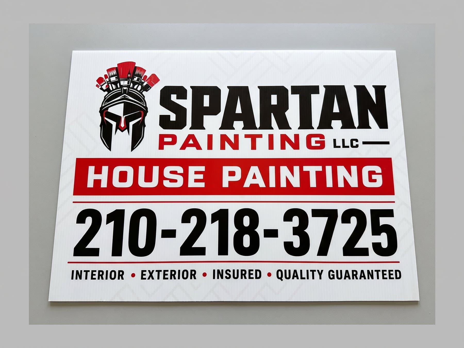Spartan Painting yard sign shot flat and centered in daylight, with the helmet mark, the red House Painting bar and the phone number set as the largest type on the panel