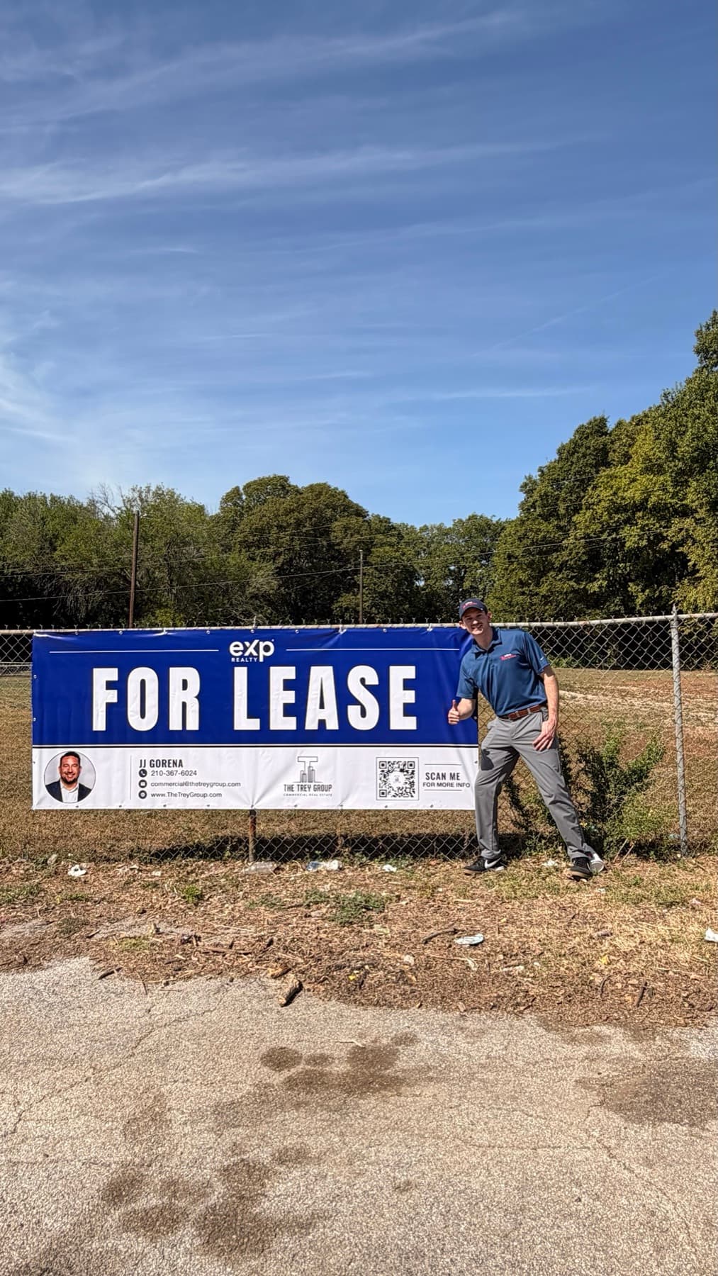 Install-day photo of the For Lease banner on the fence with the agent beside it