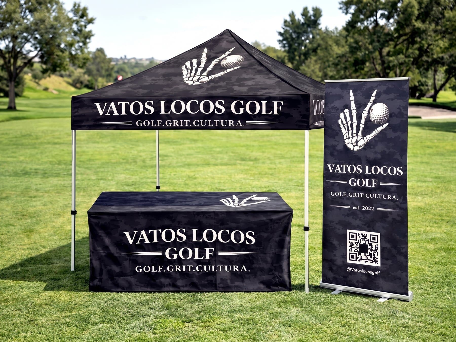 Vatos Locos Golf canopy, fitted table cover and retractable banner set up together on a sunlit fairway, all printed on the same dark camo field